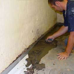 A basement waterproofer installing a perimeter drain system in Collinsville